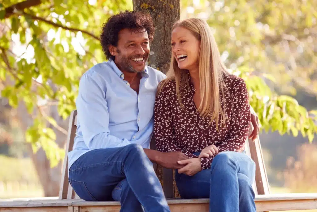 healthy relationship in recovery - happy couple sitting on a bench in the park