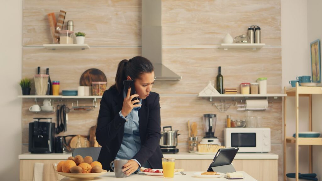 Can You Go to Rehab Without Insurance? Woman on the phone at her kitchen counter calling about addiction treatment options